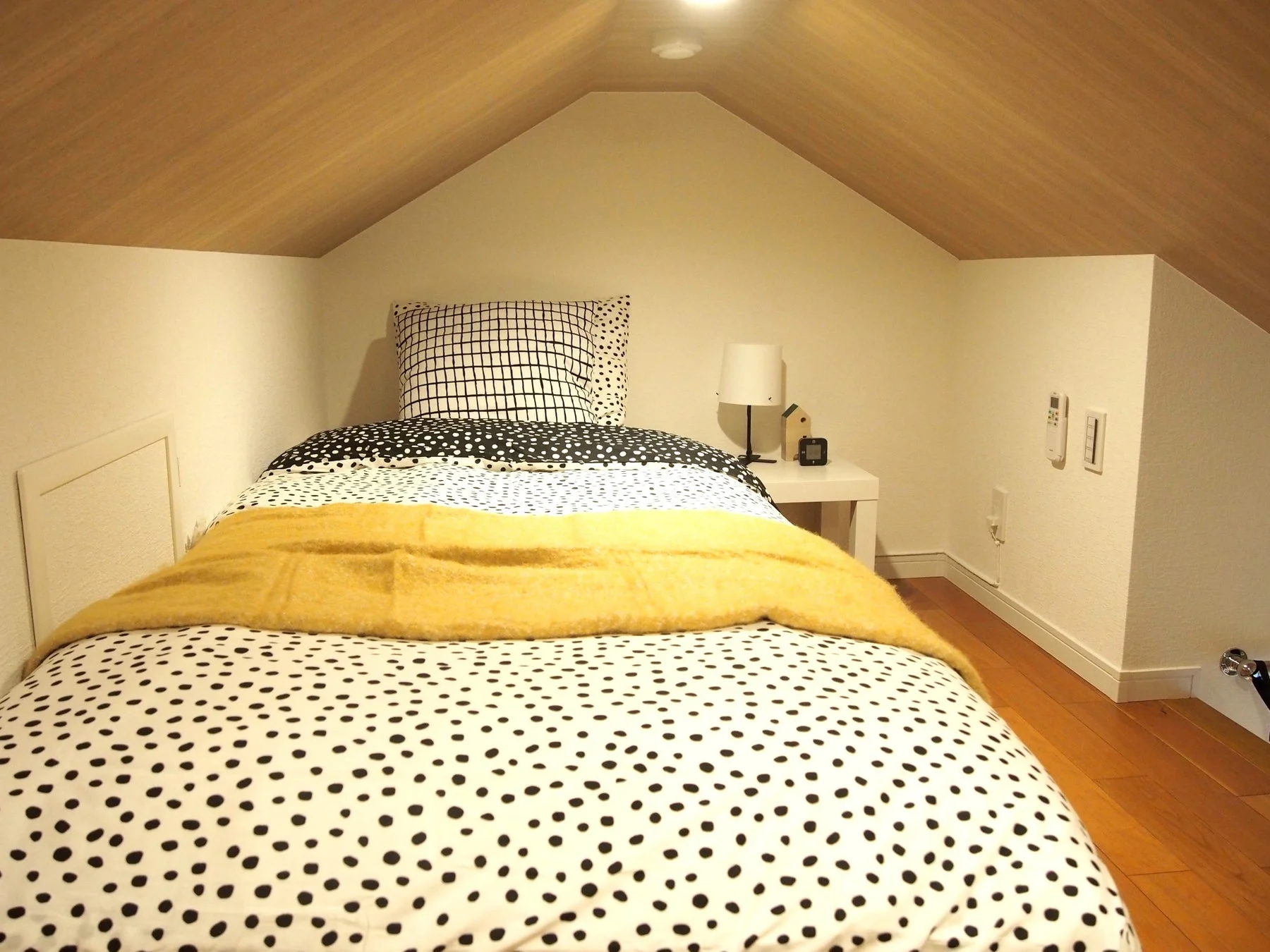 ドット柄の寝具と黄色のブランケットが敷かれたシングルベッド