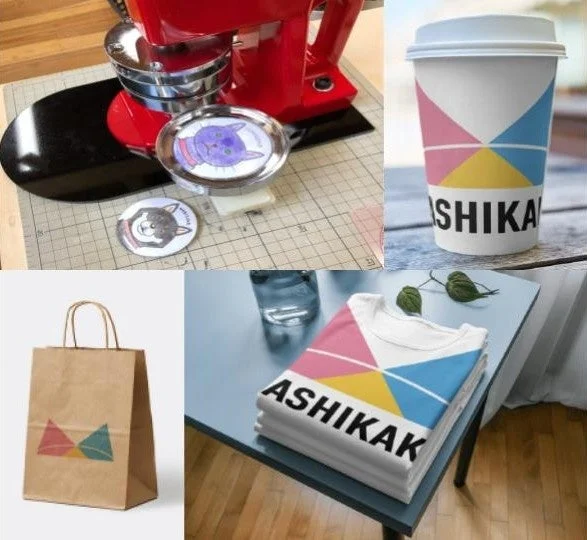 缶バッジ作成機と、同じカラフルなロゴデザインが施されたコーヒーカップ、Tシャツ、紙袋などのブランドグッズ