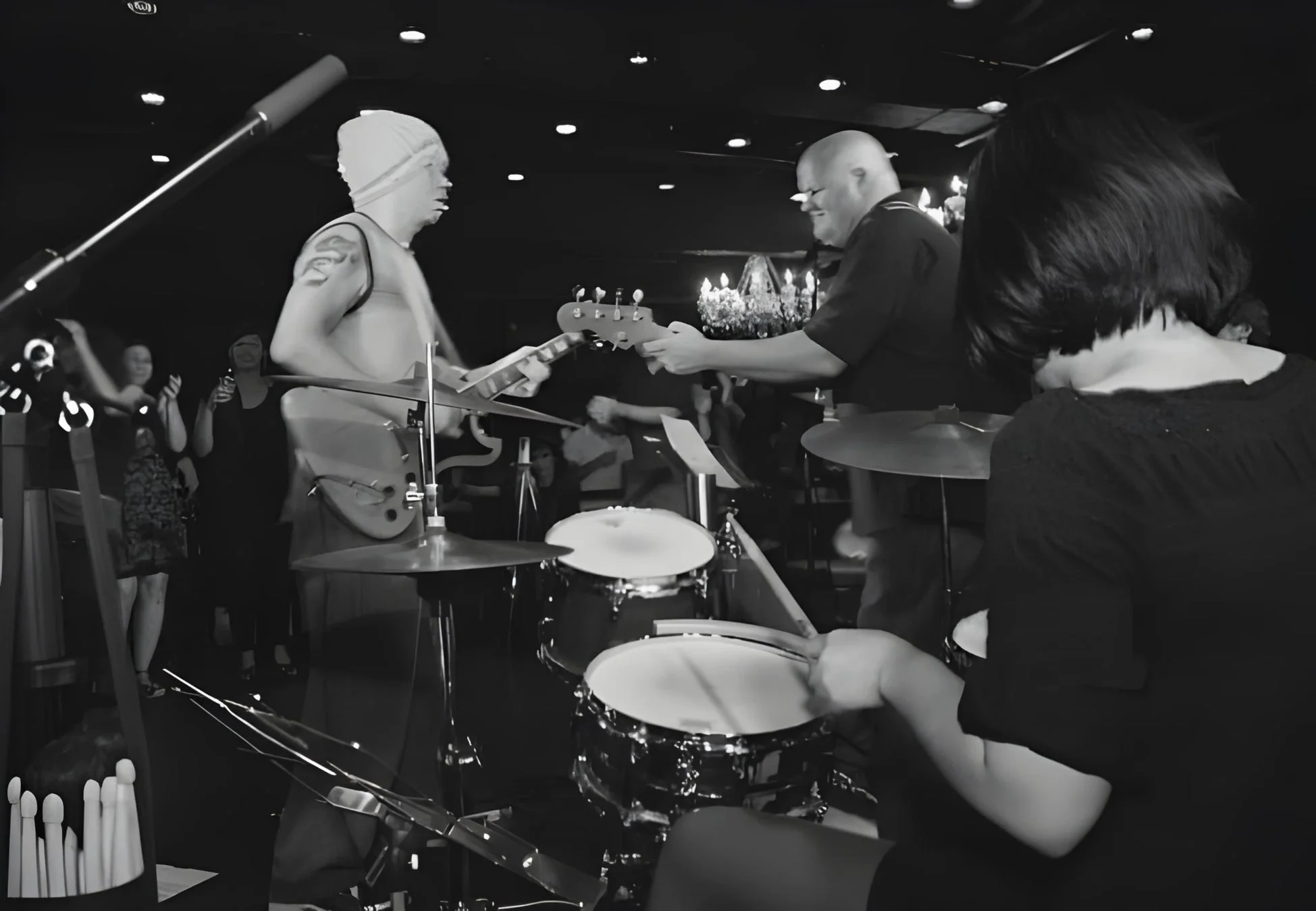 薄暗い会場でバンドがライブ演奏しているモノクロ写真