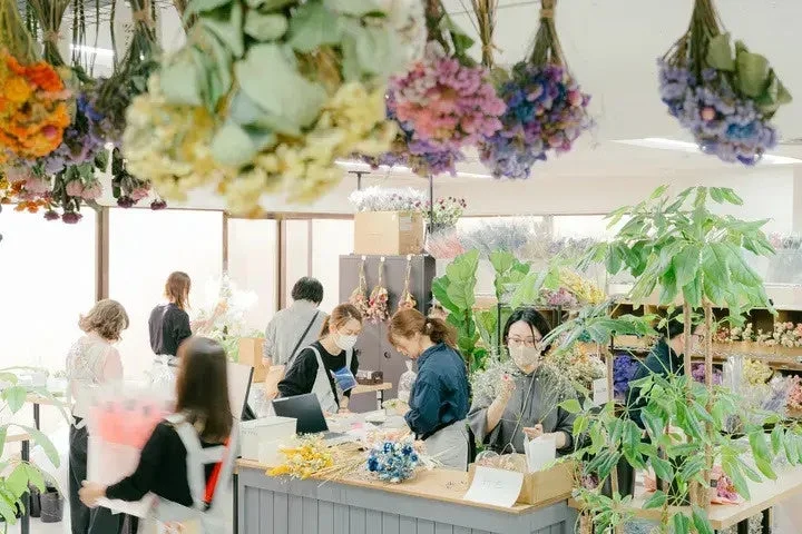 ドライフラワーが飾られた店内で作業する人々