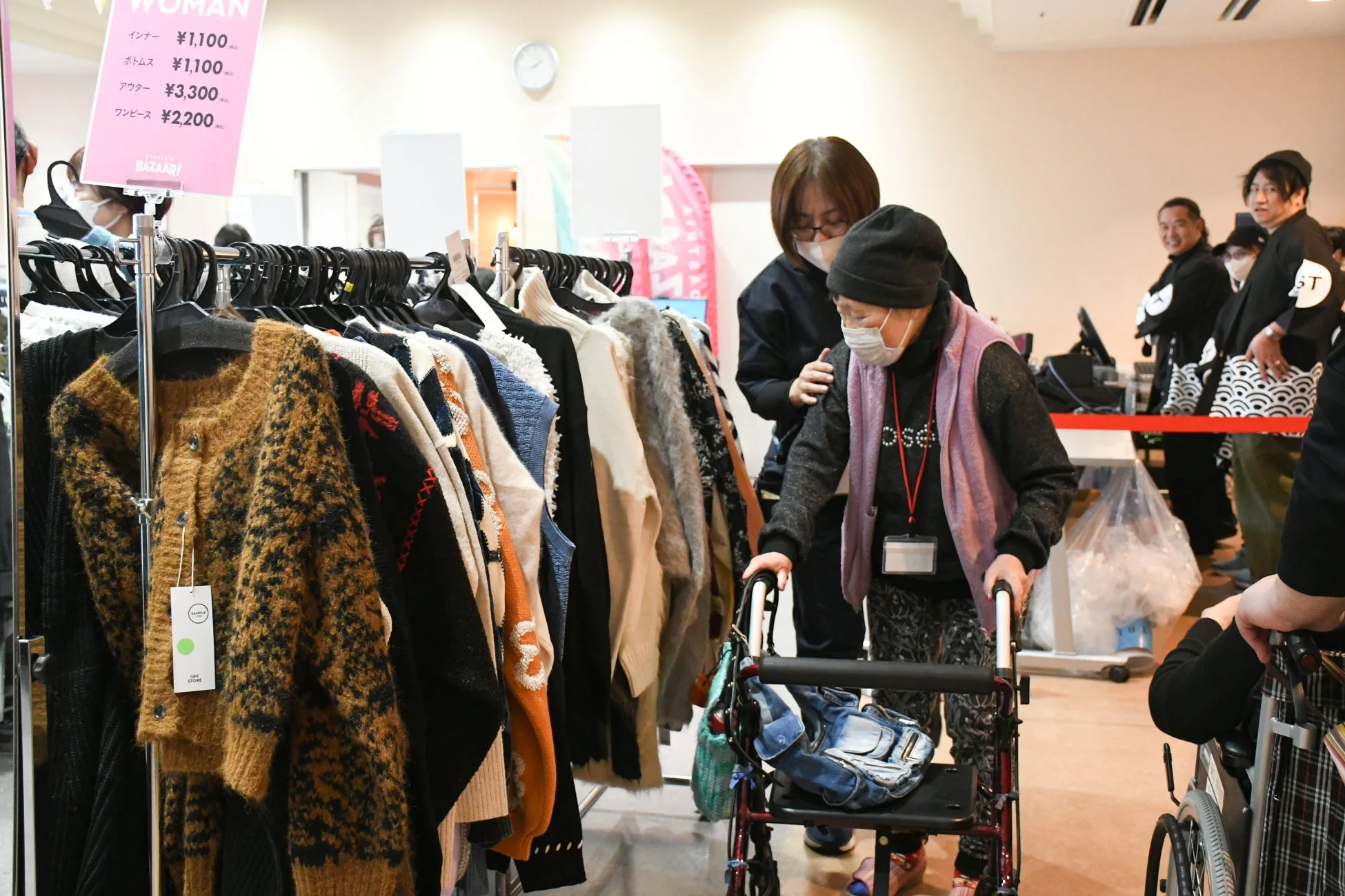 歩行器を使う高齢の女性が介助を受けながら買い物