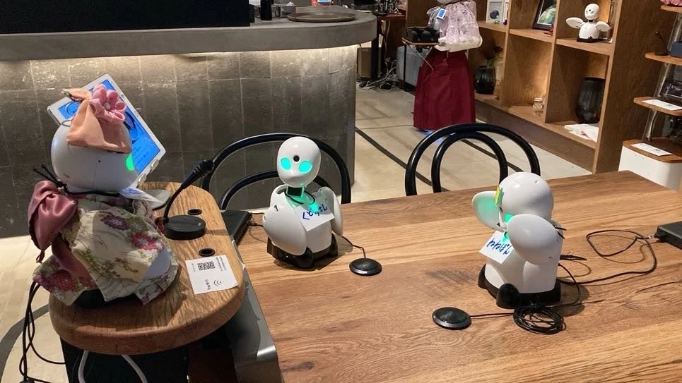 カフェのような空間で複数のロボットが配置されています。