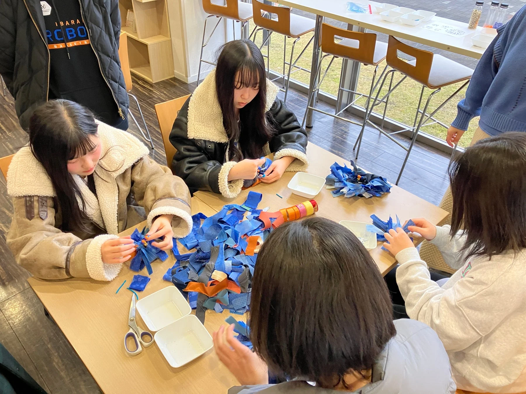 青い布でクラフト作業をする若者たち