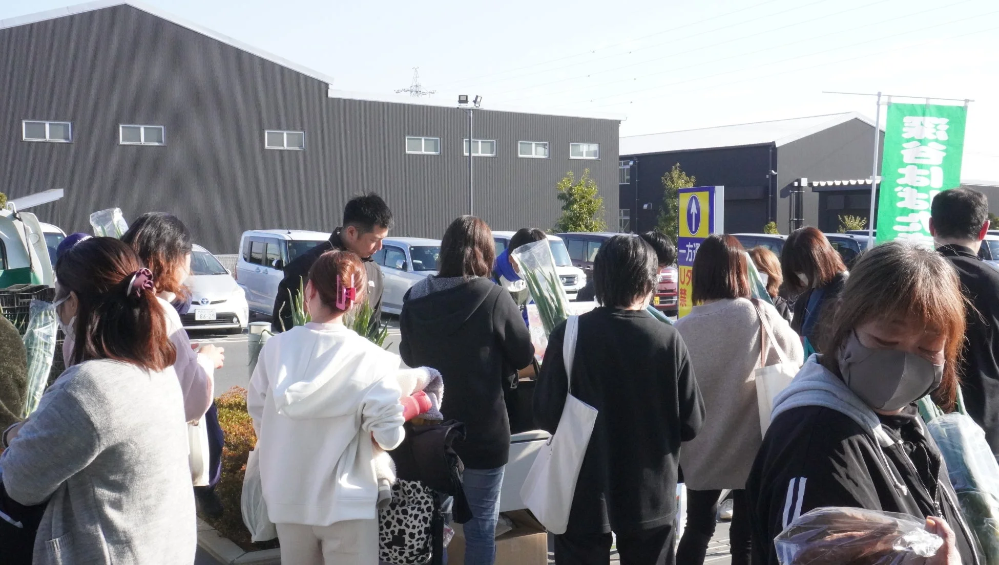 屋外の販売会で野菜を選ぶ人々