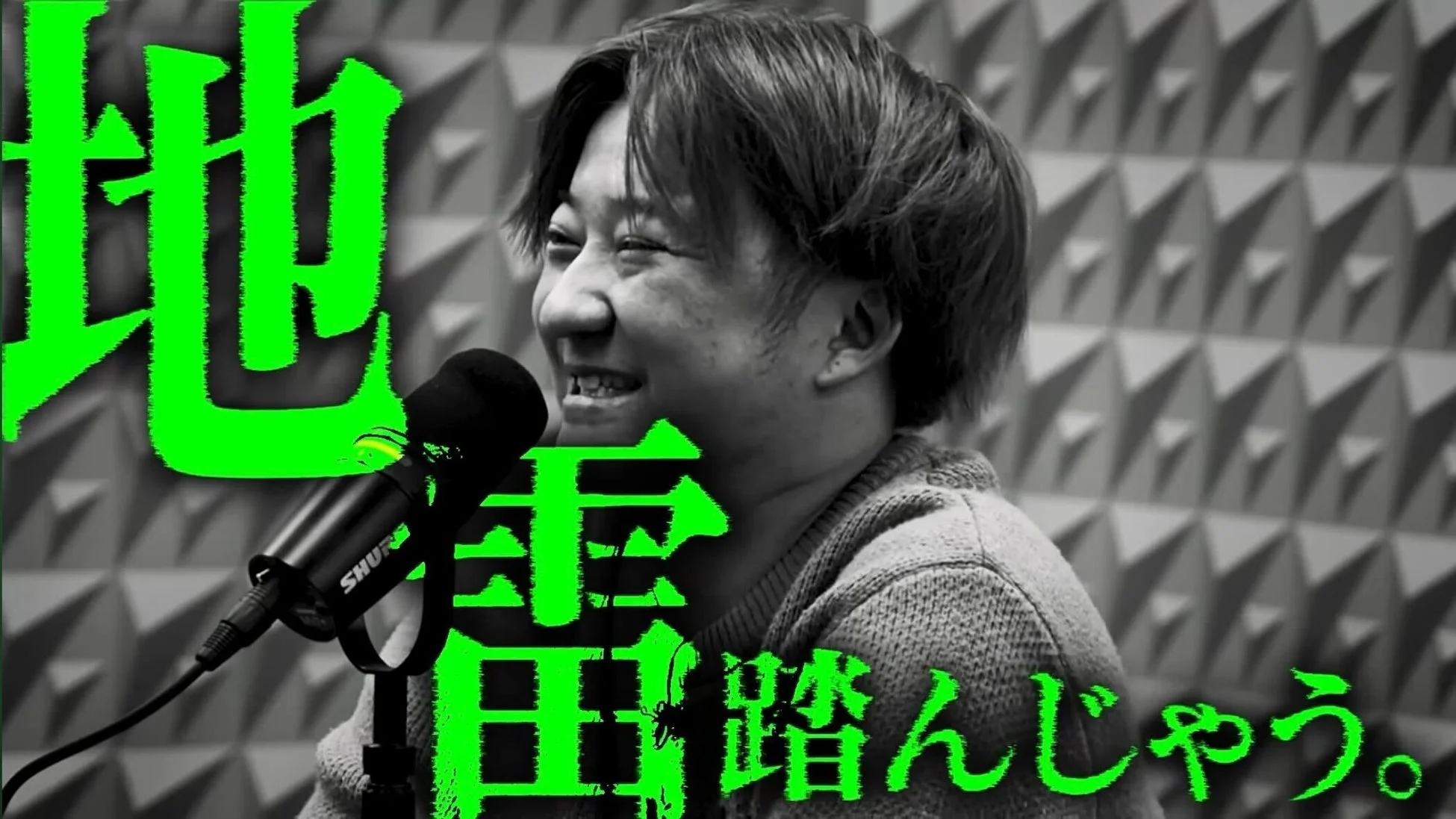 モノクロでマイクに向かって話す男性