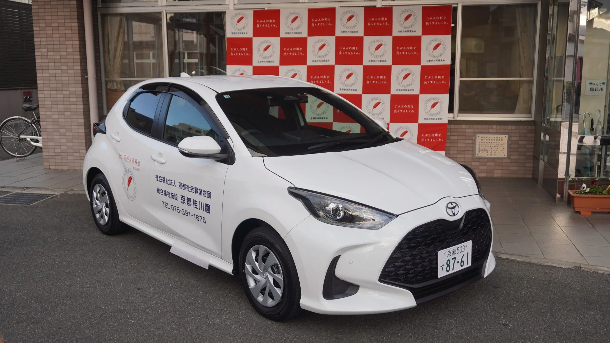 寄贈されたトヨタ ヤリスハイブリッドと施設外観