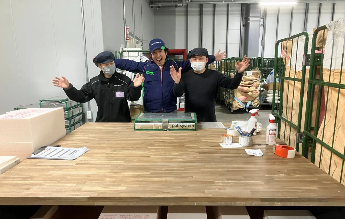 倉庫で笑顔でポーズをとる作業員たち