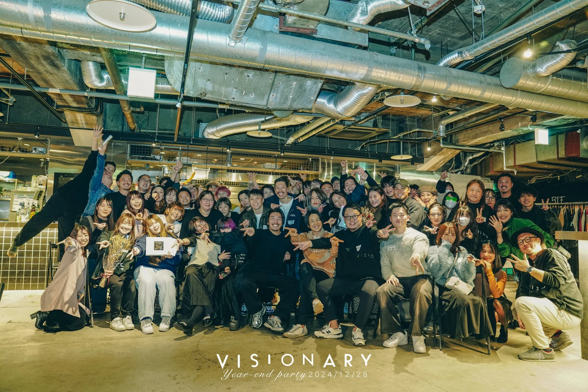 多くの人々が笑顔で集合写真を撮っている忘年会の様子