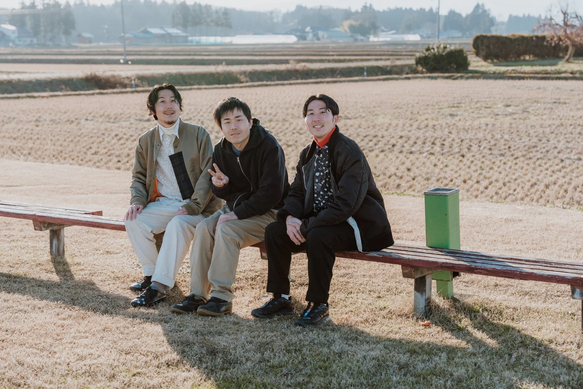 田園風景の中のベンチに座る3人の男性