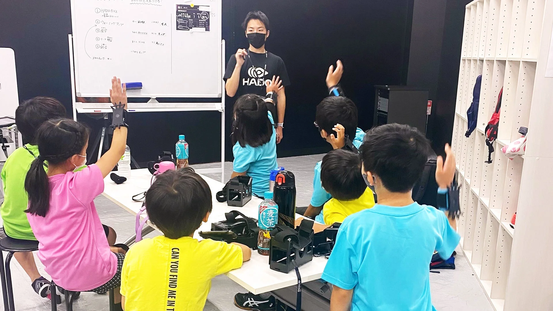 HADOのインストラクターが、ウェアラブルデバイスを装着した子供たちにARスポーツのレッスンをしている様子です。