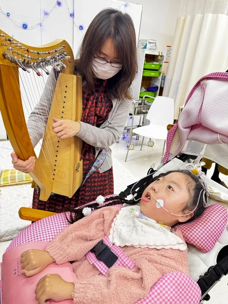 医療ケアを受ける女の子のためにハープを演奏する曽我あかね氏