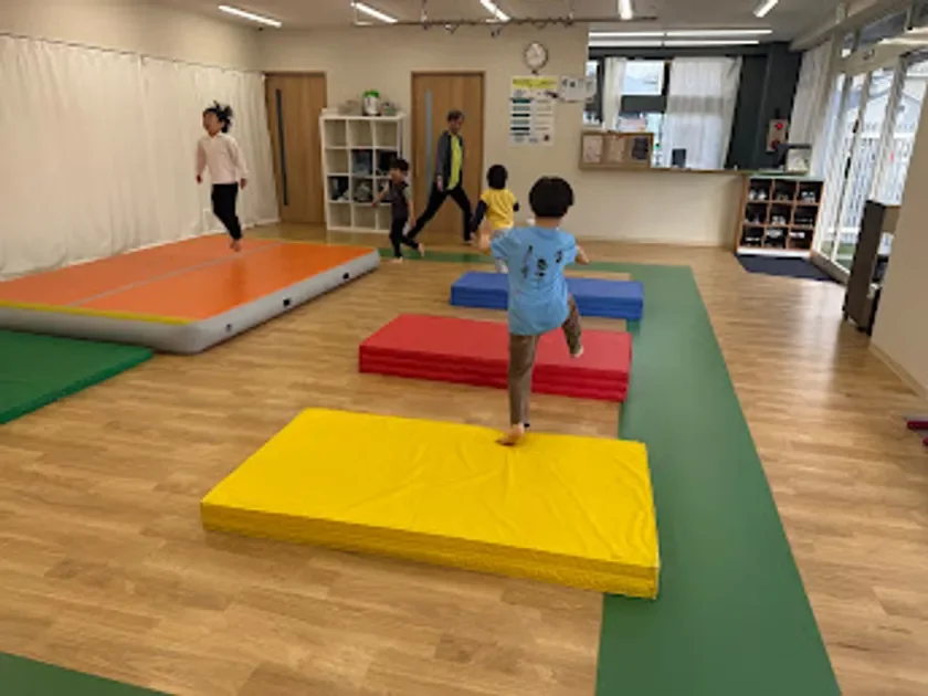 子供たちが室内で体操やマット運動を楽しんでいる様子