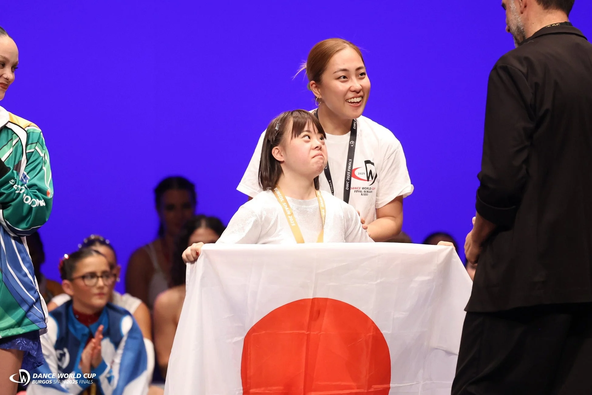 ダウン症の少女が日本国旗を掲げ、メダルを手に笑顔を見せる様子