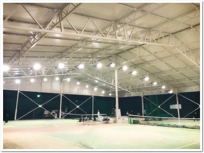 明るい照明が設置された屋内のテニスコート
