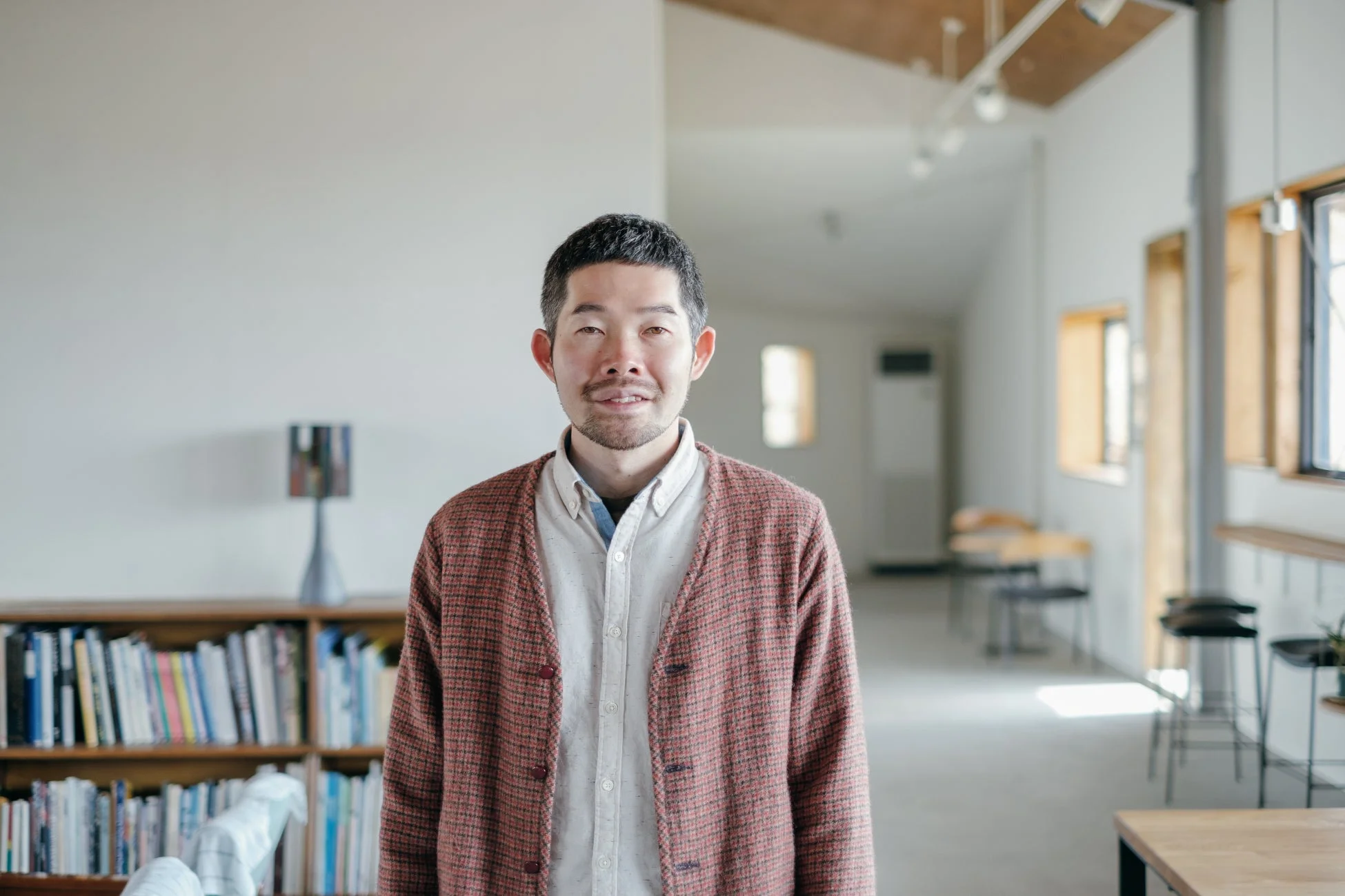 書棚と窓を背景に微笑む男性