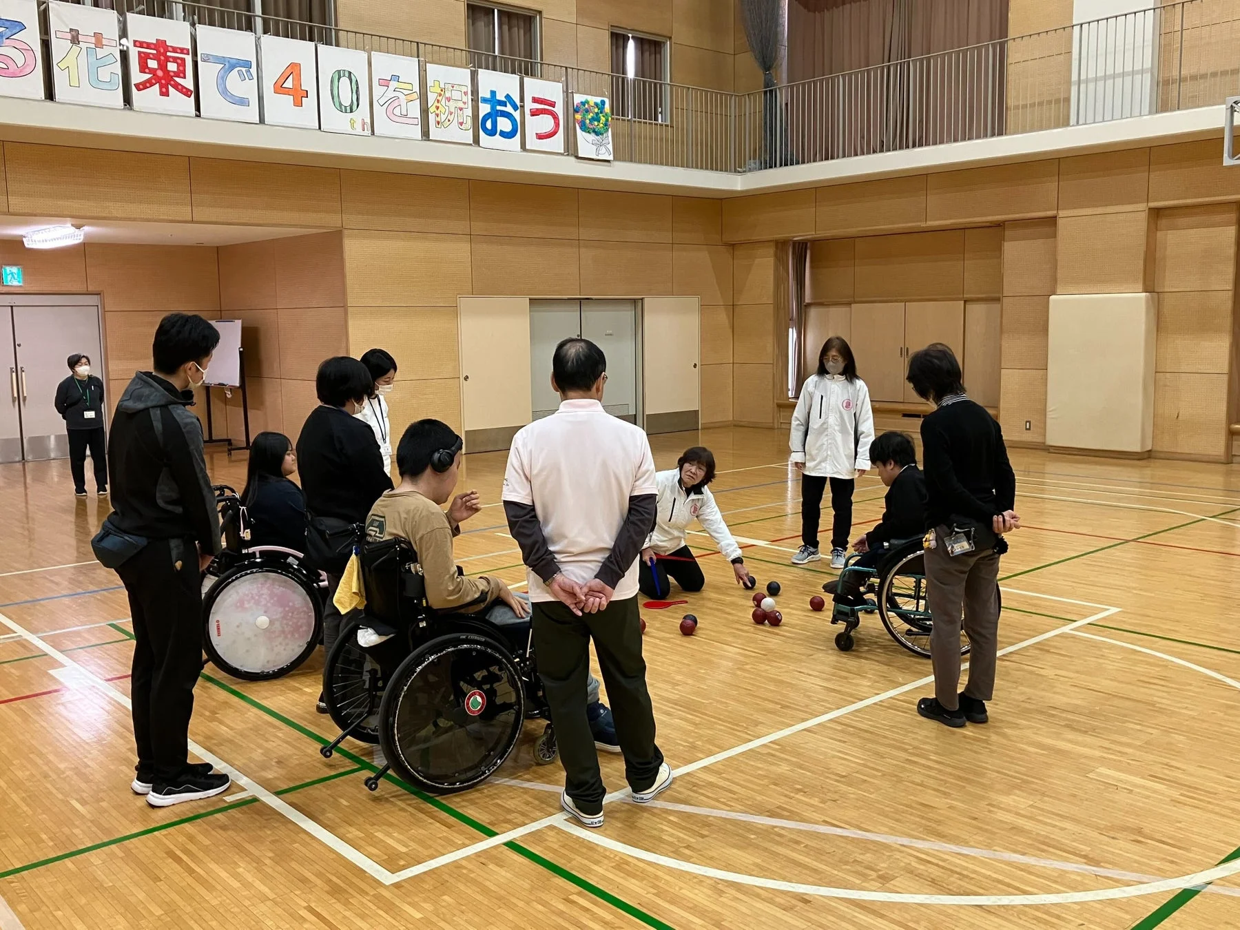 体育館で車椅子利用者を含む人々がボッチャを楽しんでいます