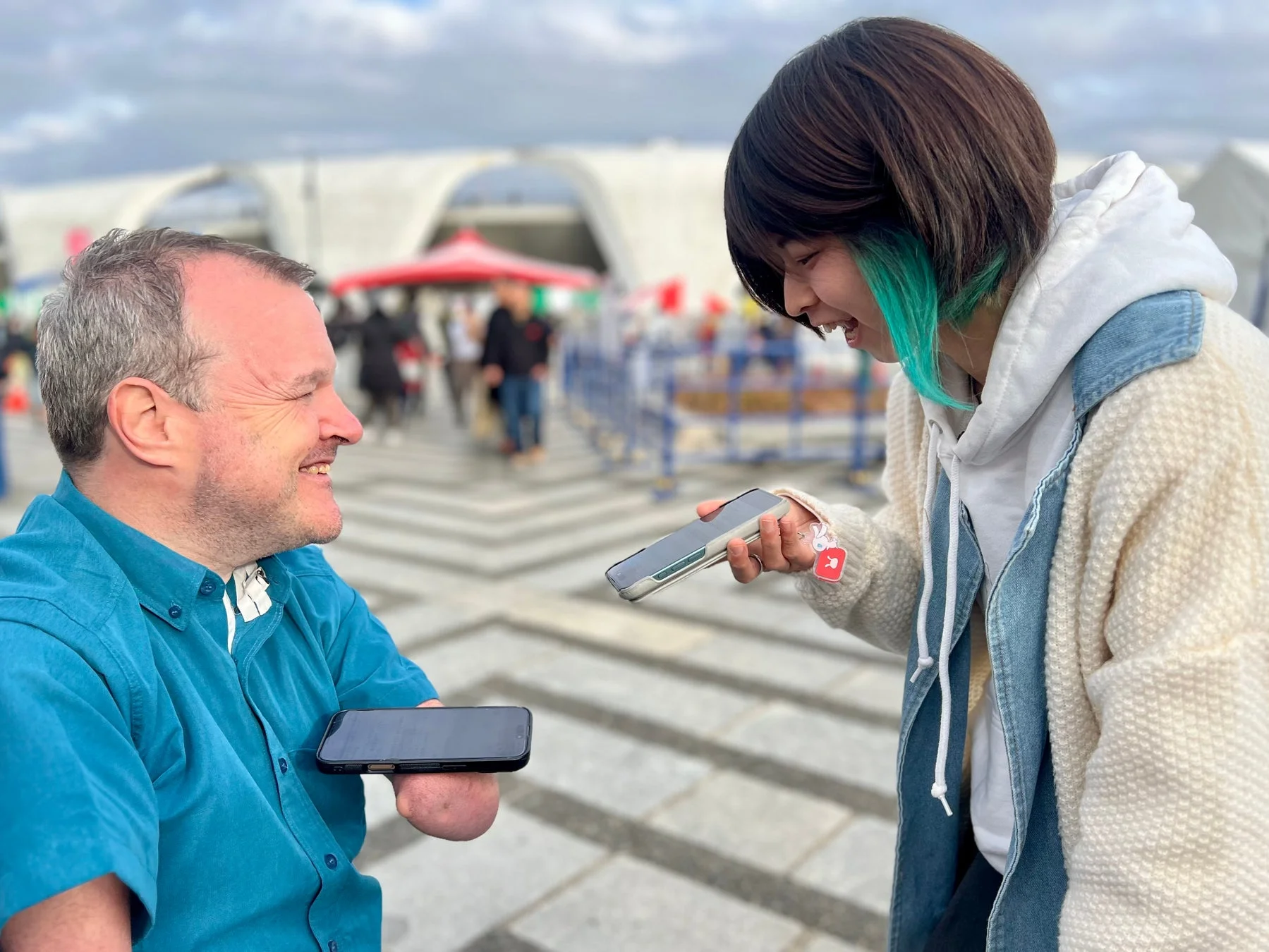 屋外で笑顔で会話する二人の人物