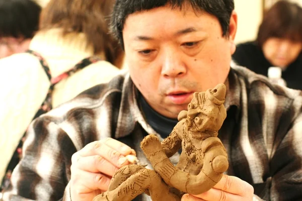 男性が粘土で人形制作