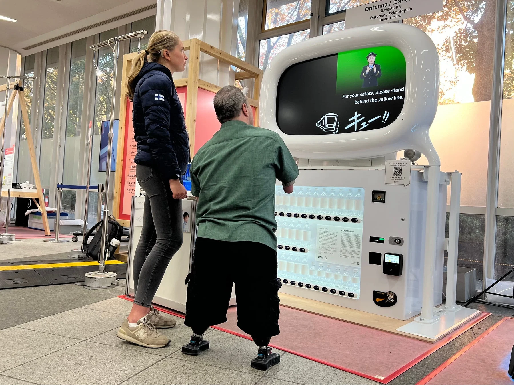 デジタルサイネージ付き自動販売機を操作する人物