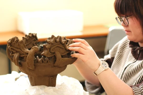 女性が粘土でシーサー制作