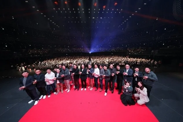 多くの人々がステージでポーズをとっている様子