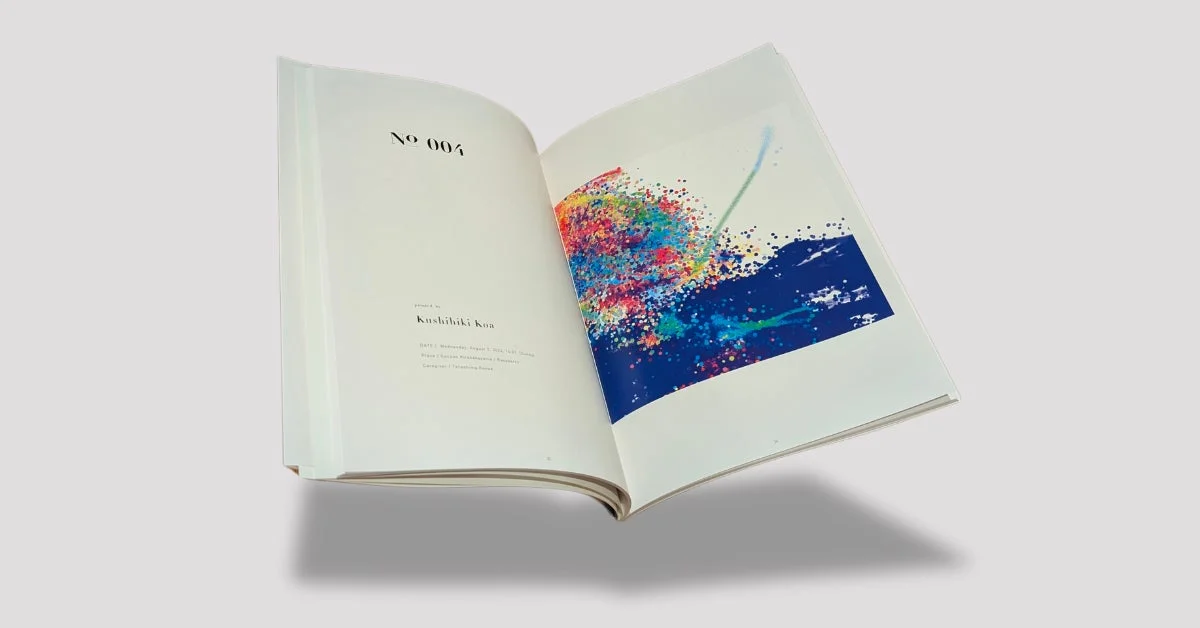 白地のページが開かれた本が宙に浮いているような構図の画像です。左ページにはテキストがあり、右ページには青い背景にカラフルな飛沫が描かれた抽象的なアート作品が掲載されています。