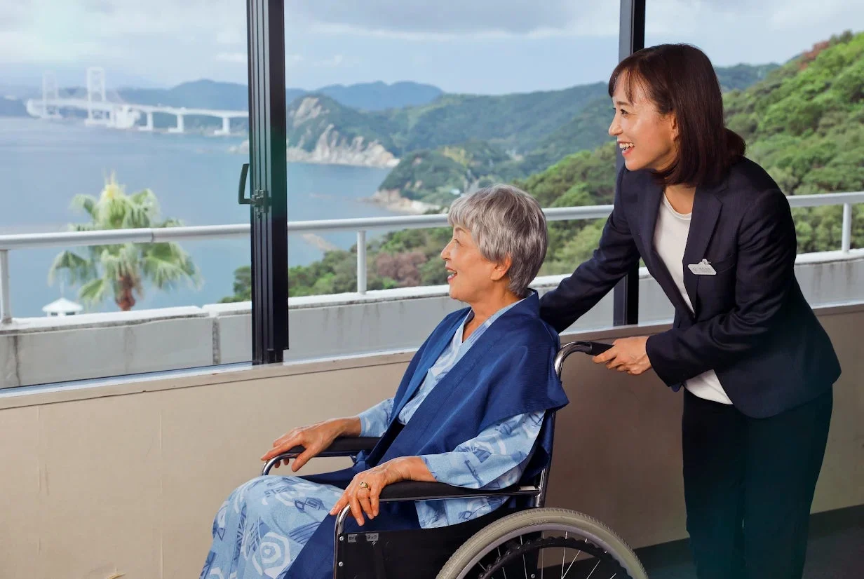 車椅子に乗った高齢女性が海辺の景色を眺める