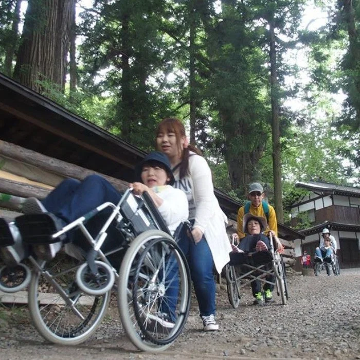 森の中の小道を車椅子で散歩する人々