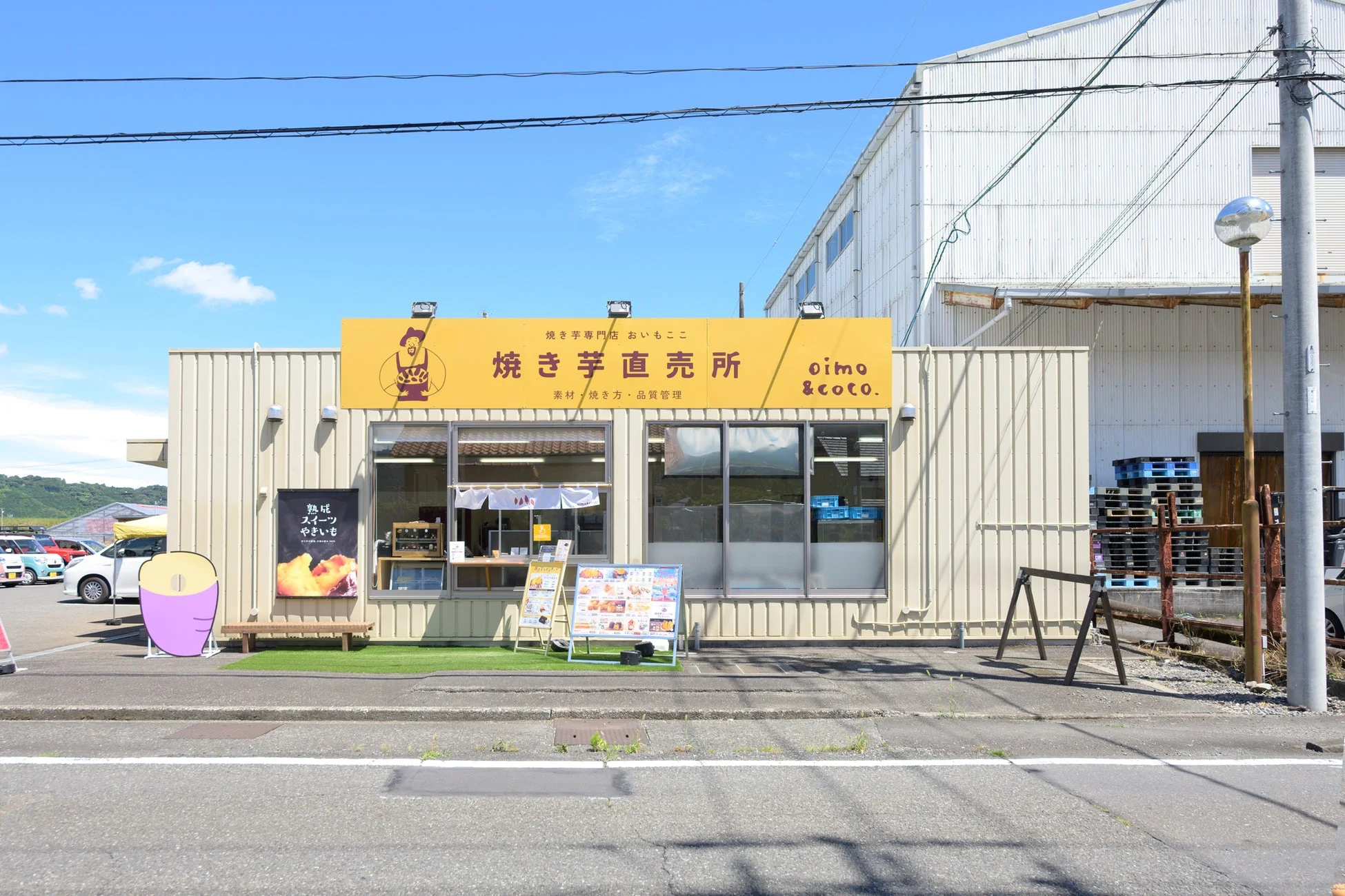 青空の下、道路沿いに立つ「焼き芋専門店 おいもここ」の店舗外観