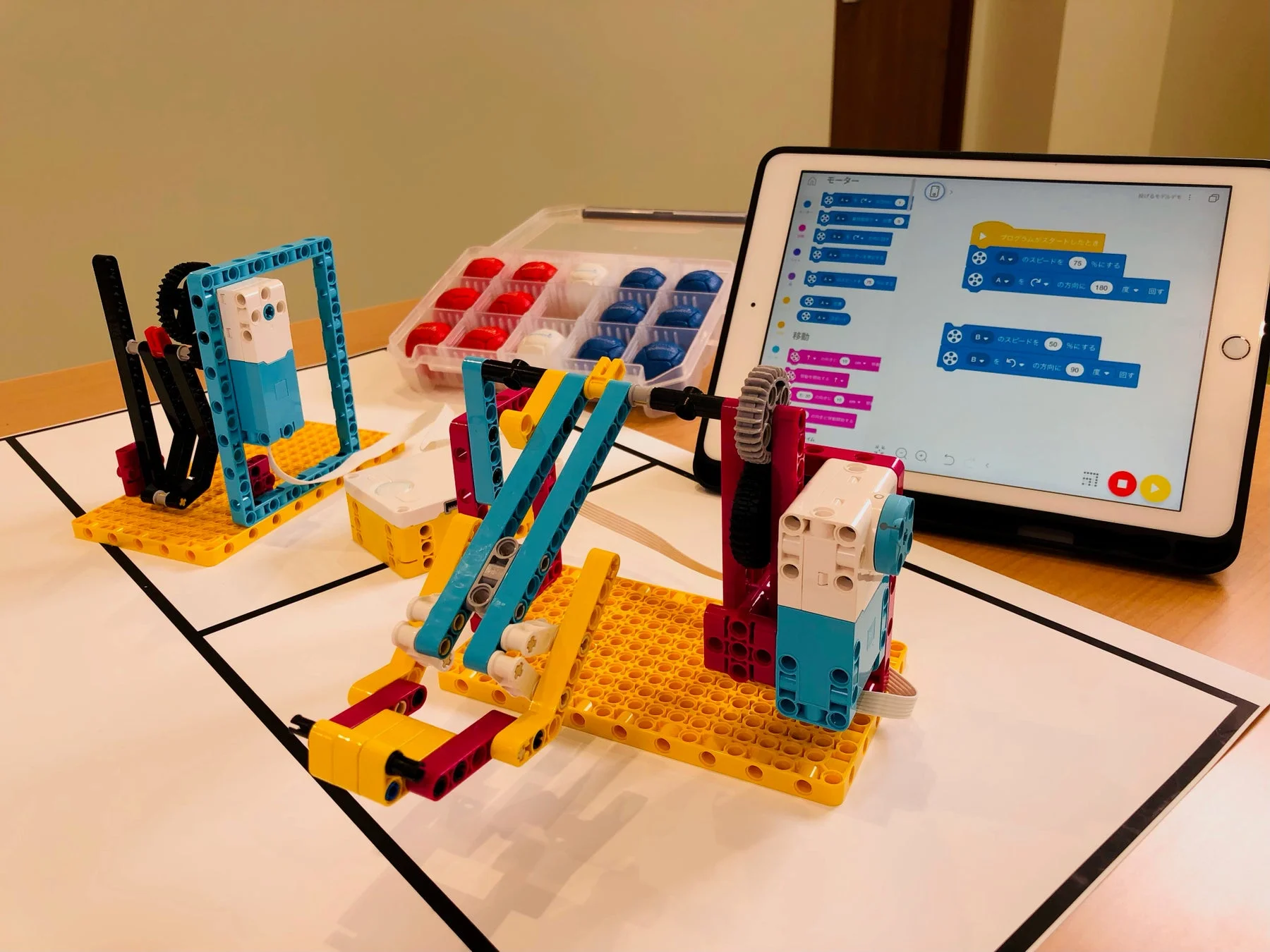 ブロックプログラミングの画面が表示されたiPadとロボット