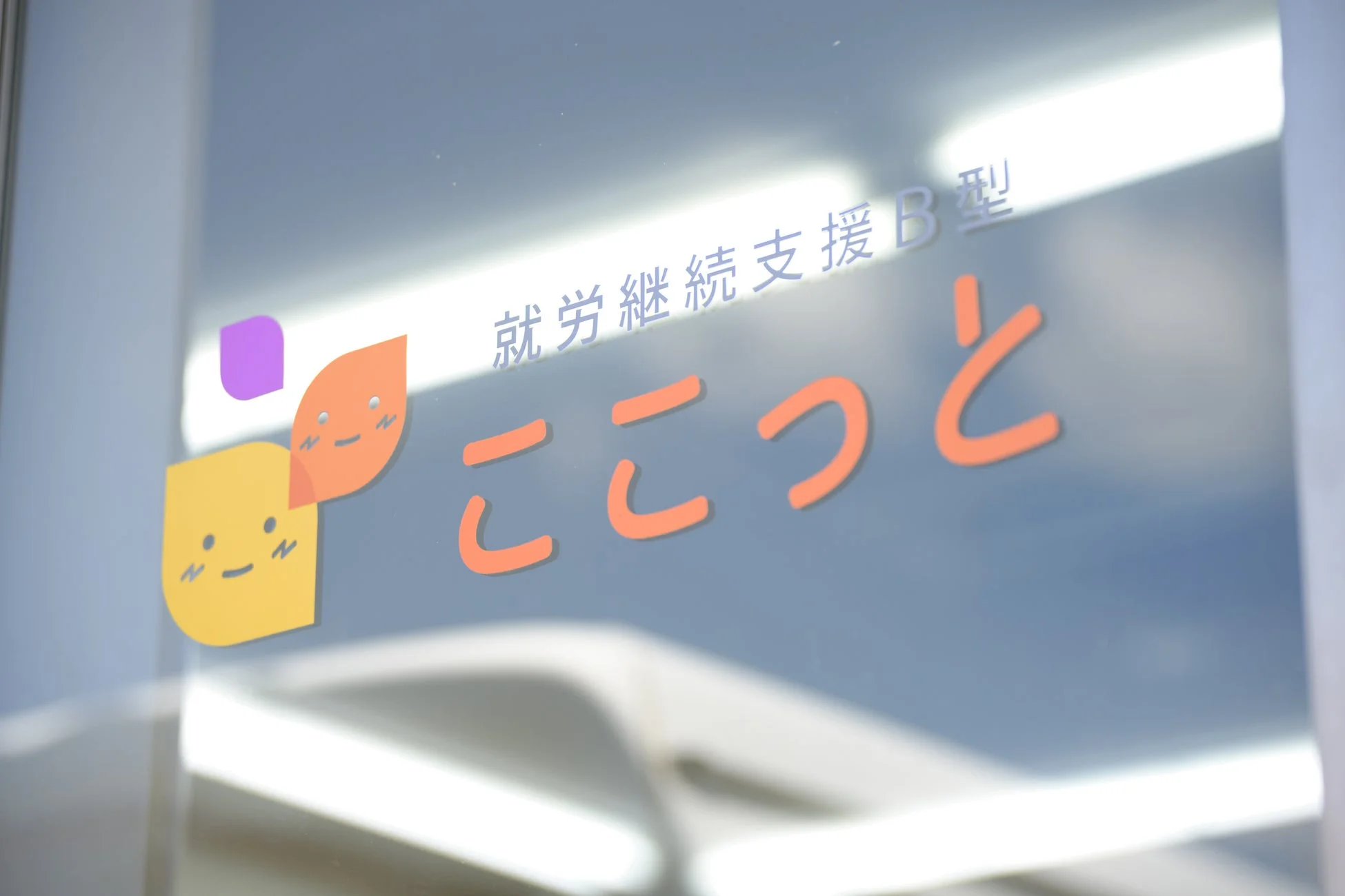 ガラスに「就労継続支援B型 ここっと」という文字と、可愛らしいキャラクターのロゴ