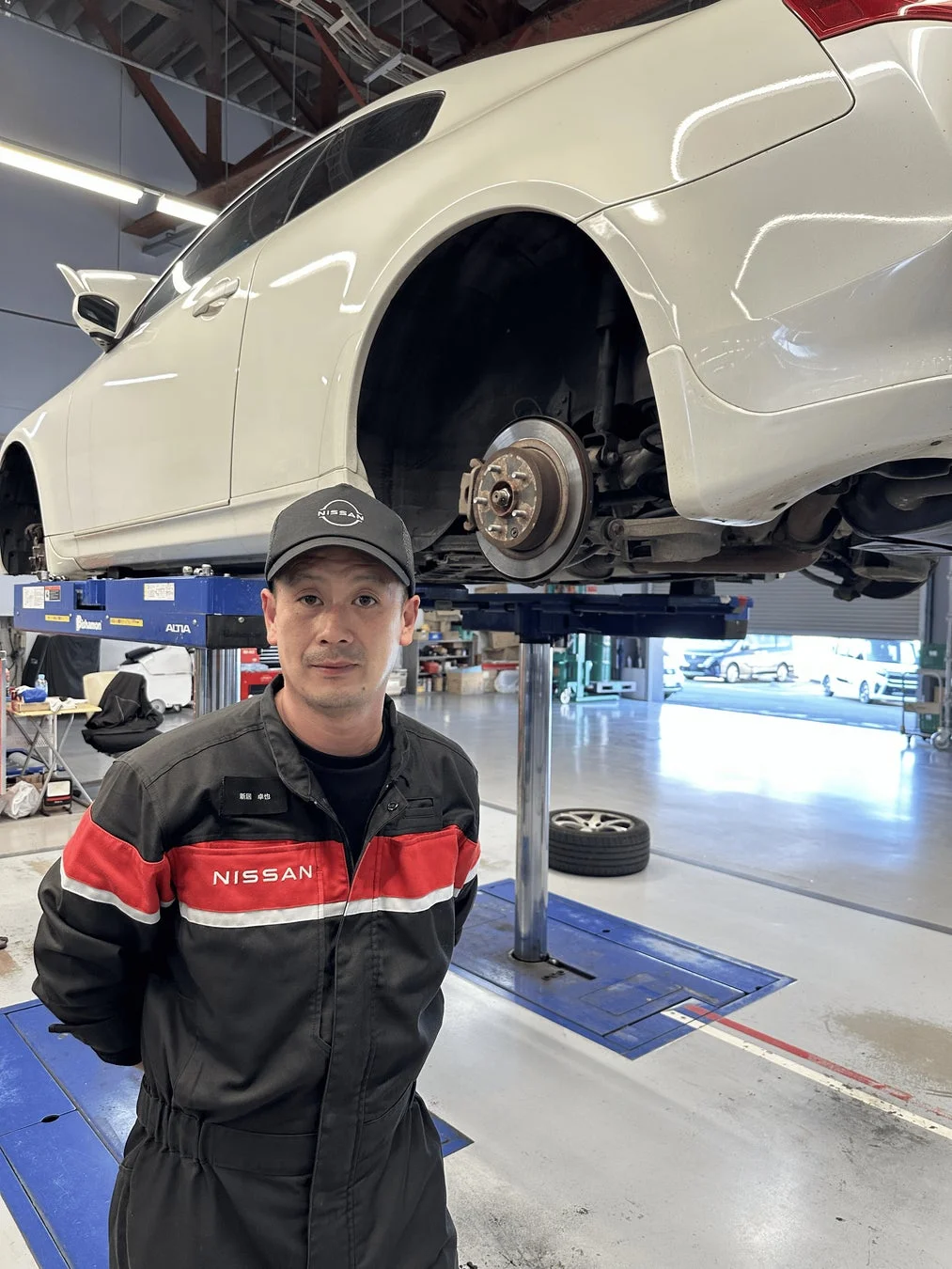 整備工場で日産の作業着を着た男性が立っている様子