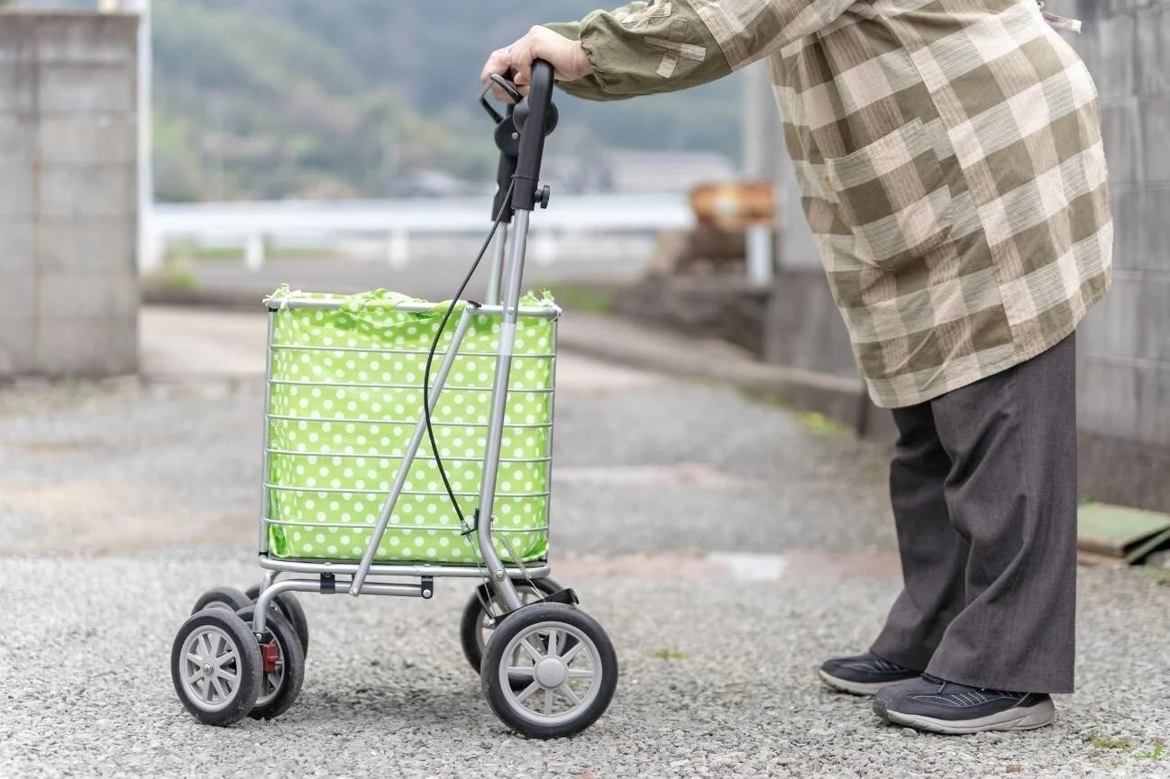 緑色の水玉模様のショッピングカートを押して歩く高齢者
