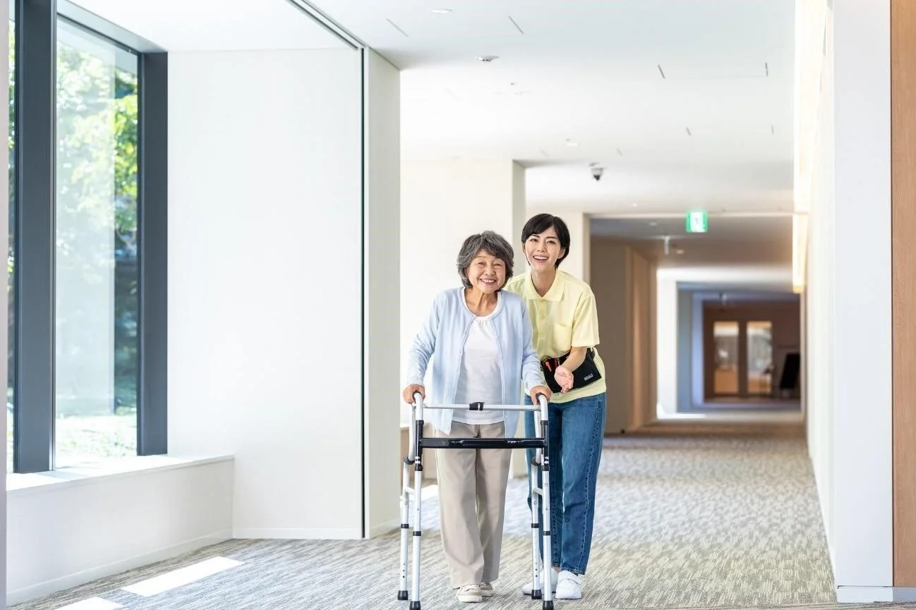 歩行器を使用する高齢女性をサポートする介護士
