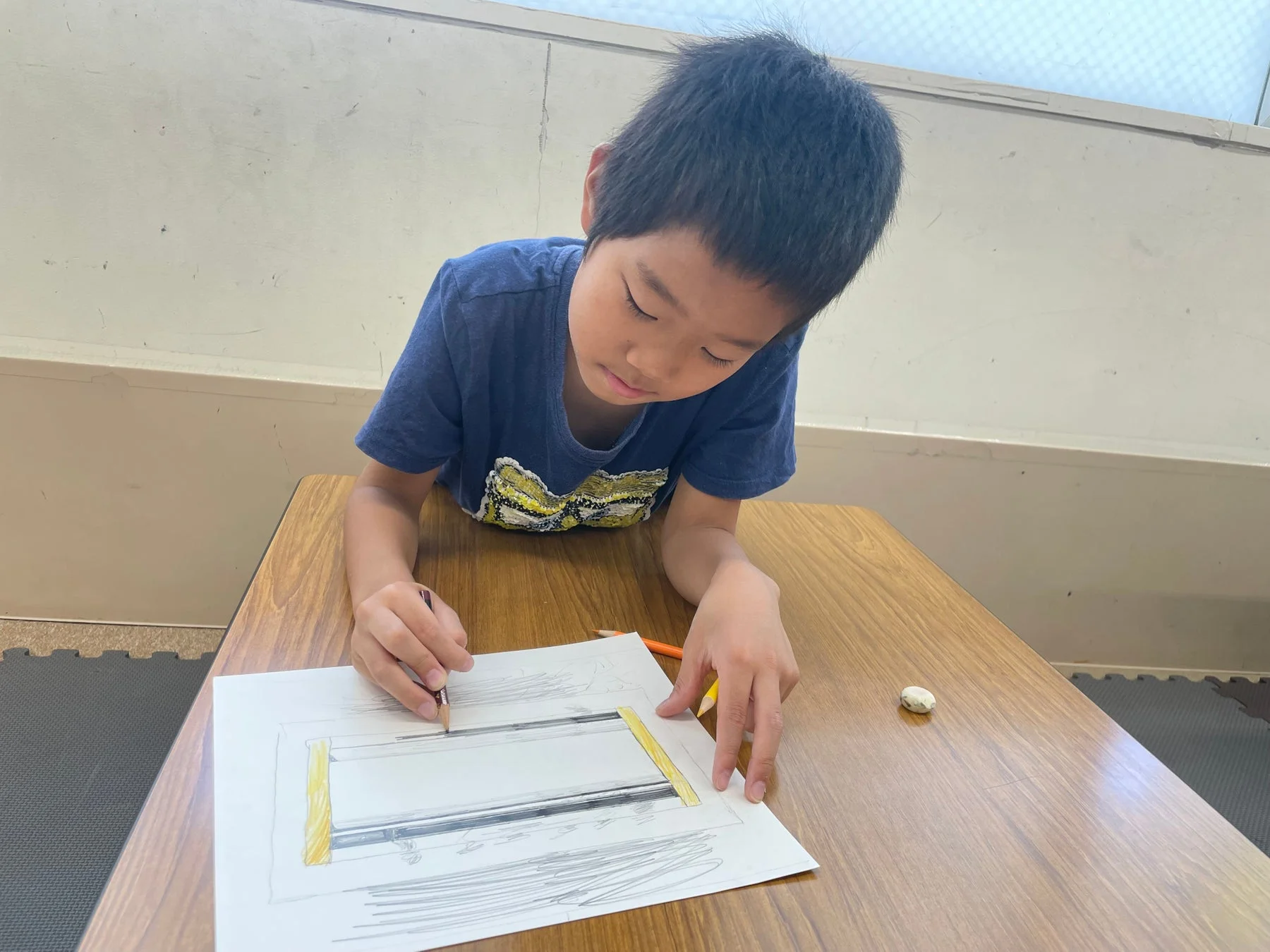 少年が机で絵を描く様子