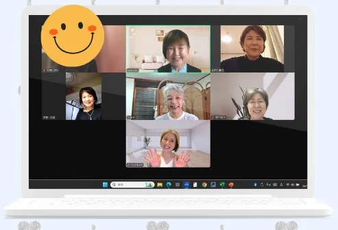 白いノートパソコンの画面にオンラインビデオ通話の様子が映し出されており、バーチャルな交流の場面