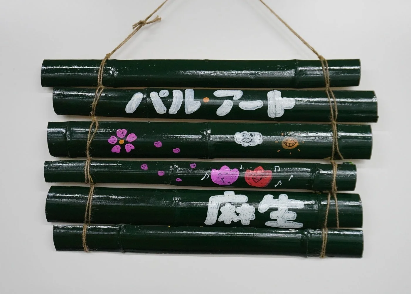 暗い緑色の竹を麻紐で繋いで作られた手作りの吊り下げ飾りです