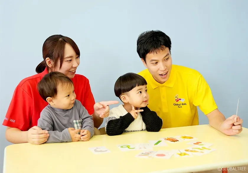 保育士と子どもたちがカード遊びをする様子