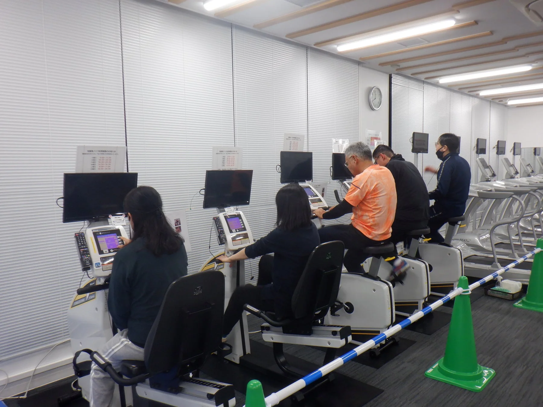 フィットネス施設でエアロバイクを使用する人々