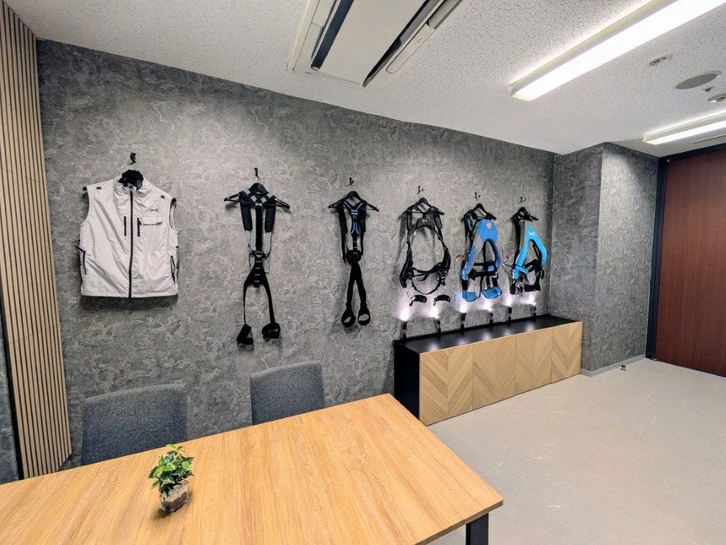 現代的な空間の壁に、作業補助用のウェアラブルデバイスや外骨格が複数展示されている画像