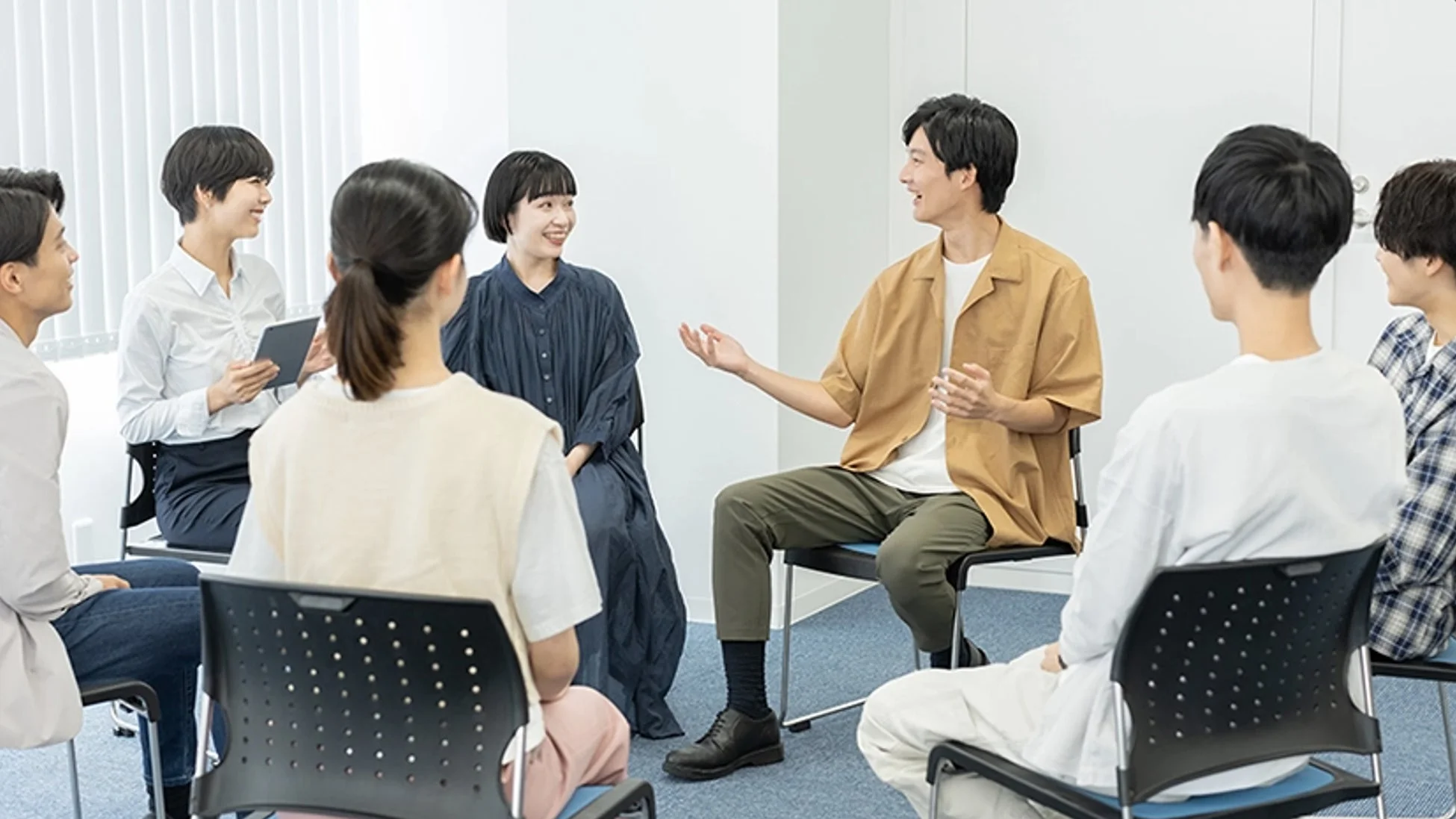 複数の若い男女が円になって座り、笑顔で活発に話し合っている様子