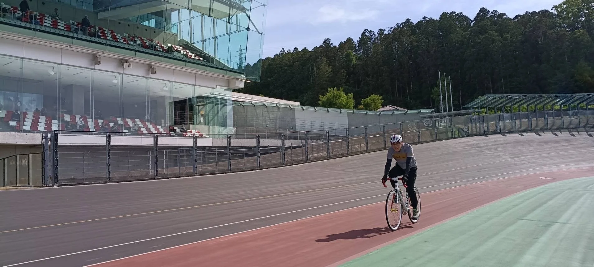 ベロドロームのような自転車競技場で、ヘルメットを着用した人がロードバイクに乗ってトラックを走行している様子