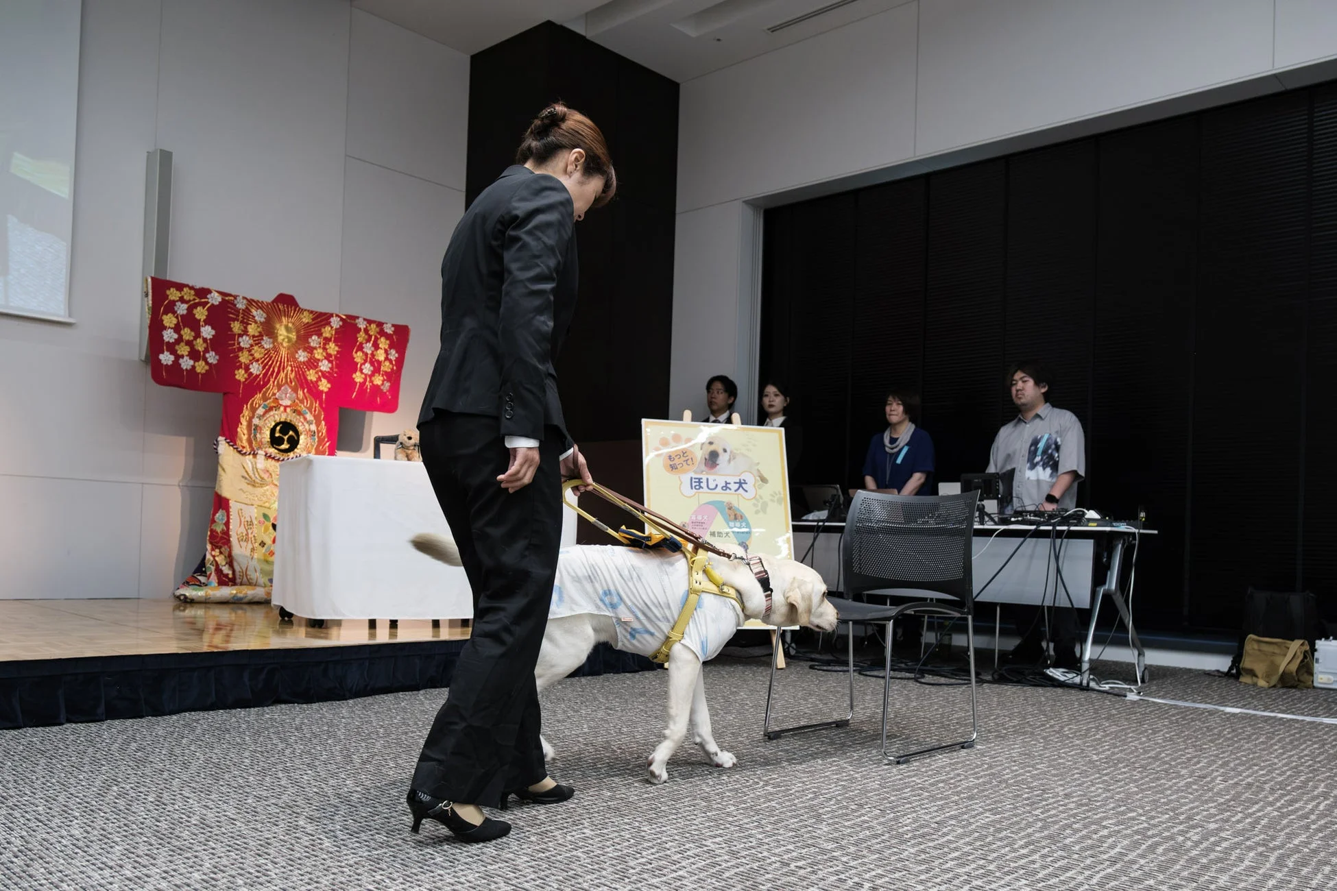 補助犬のデモンストレーションを行う女性とラブラドールレトリバー
