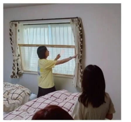 窓のカーテンを調整する女性