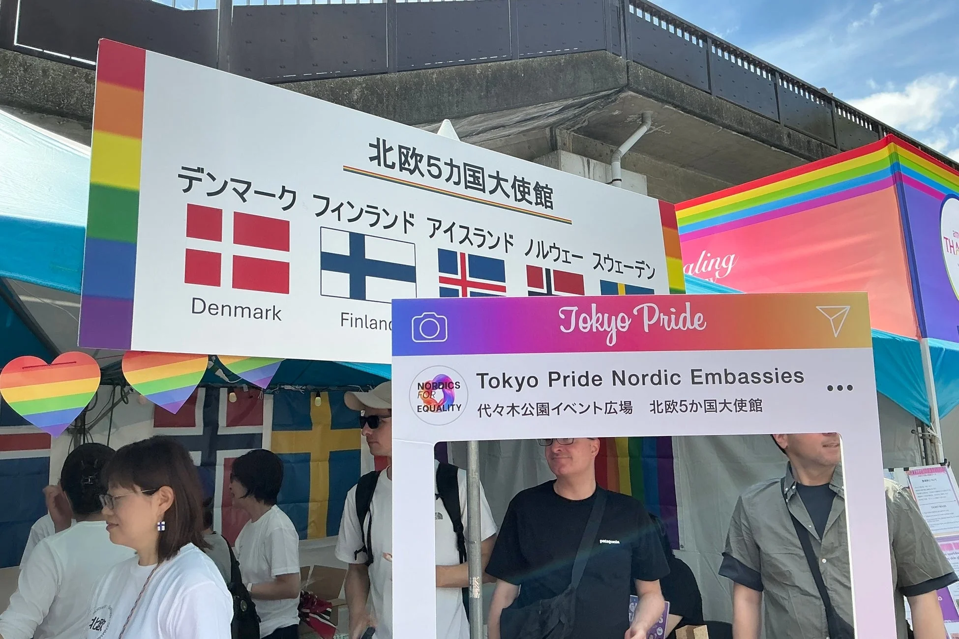 東京プライドの会場で、北欧5カ国大使館のブースが写っています。デンマーク、フィンランドなど北欧各国の国旗とレインボーカラーの装飾が見られ、来場者がイベントを楽しんでいる様子が伝わります。
