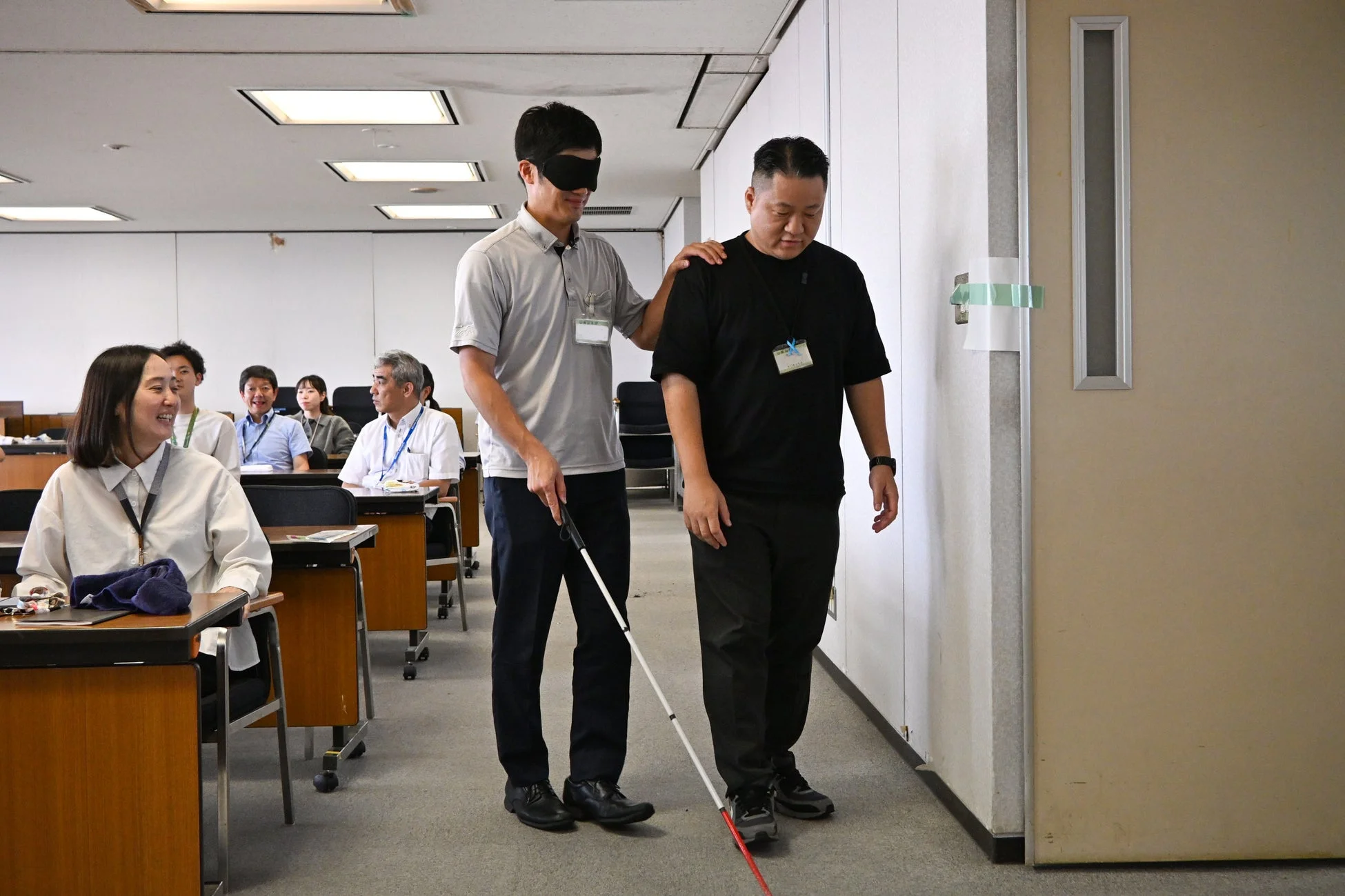 オフィス内で白杖を使い誘導される男性