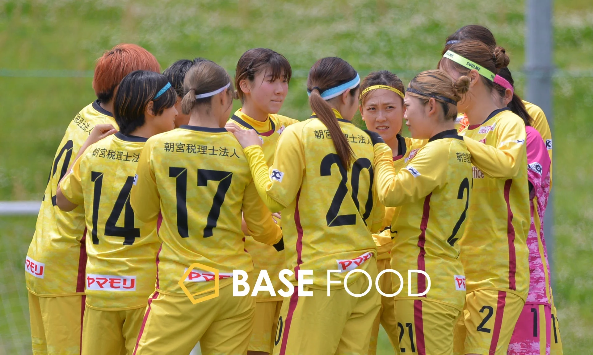 黄色いユニフォームを着た女性サッカー選手たちがフィールドで円陣を組んでいる様子