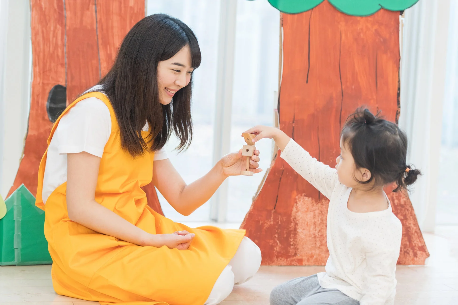 女性と子供が木のおもちゃで遊んでいる様子