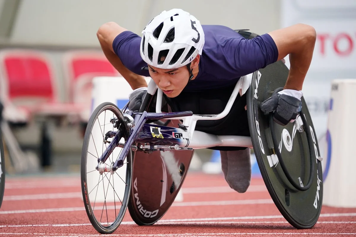 車いす陸上競技の選手が、トラック上でスタートラインに構え、真剣な表情で集中している瞬間