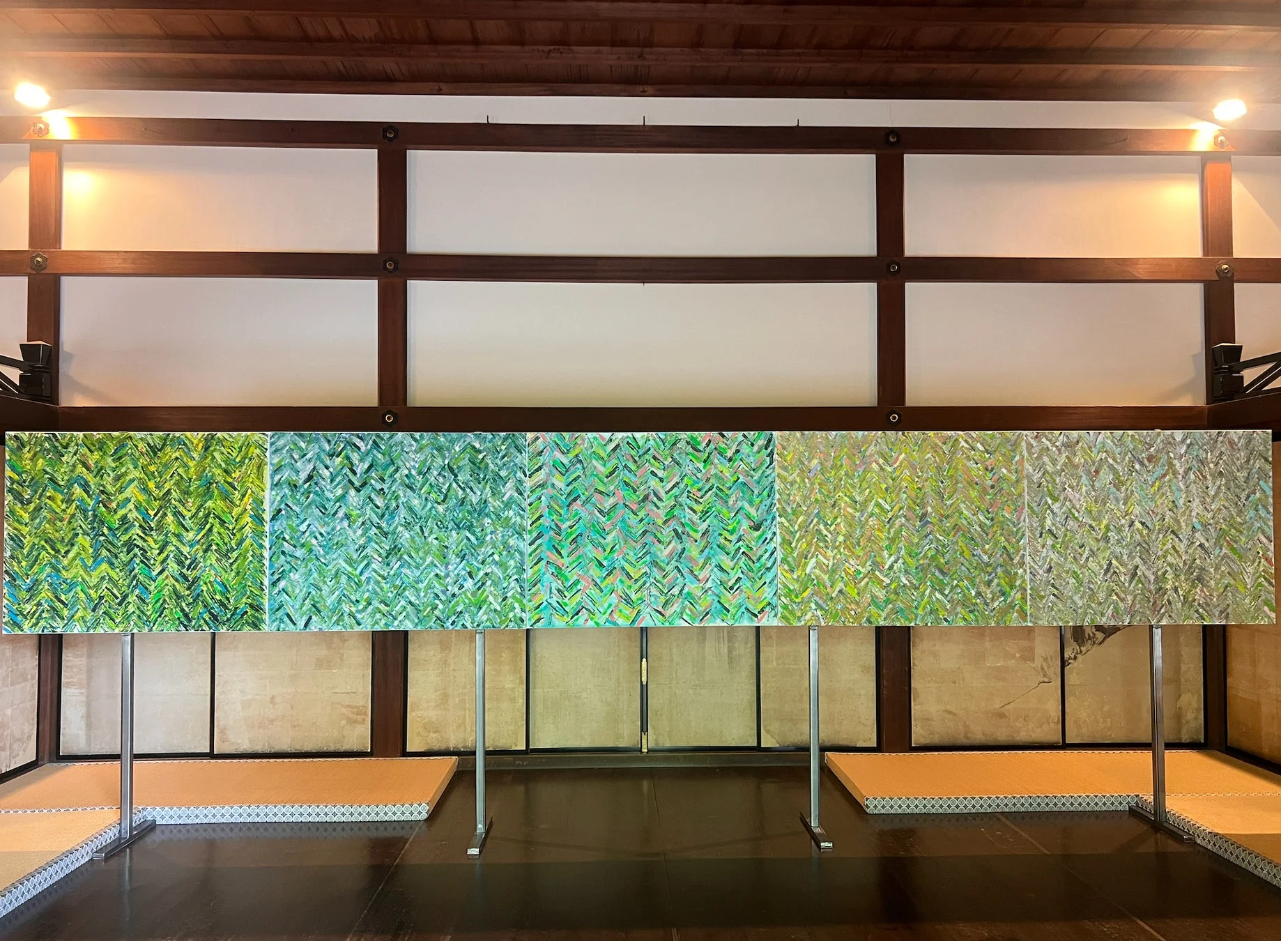 伝統的な日本家屋の空間に展示された、緑から青緑へと変化するグラデーションが美しい抽象的な現代アート作品。ヘリンボーンのような模様が特徴です。
